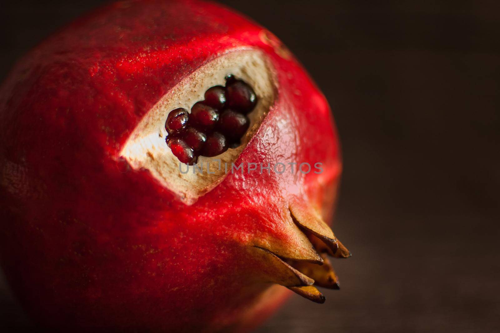Juicy garnet ripe pomegranate fruit on wooden background. Healthy eating, exotic fruits