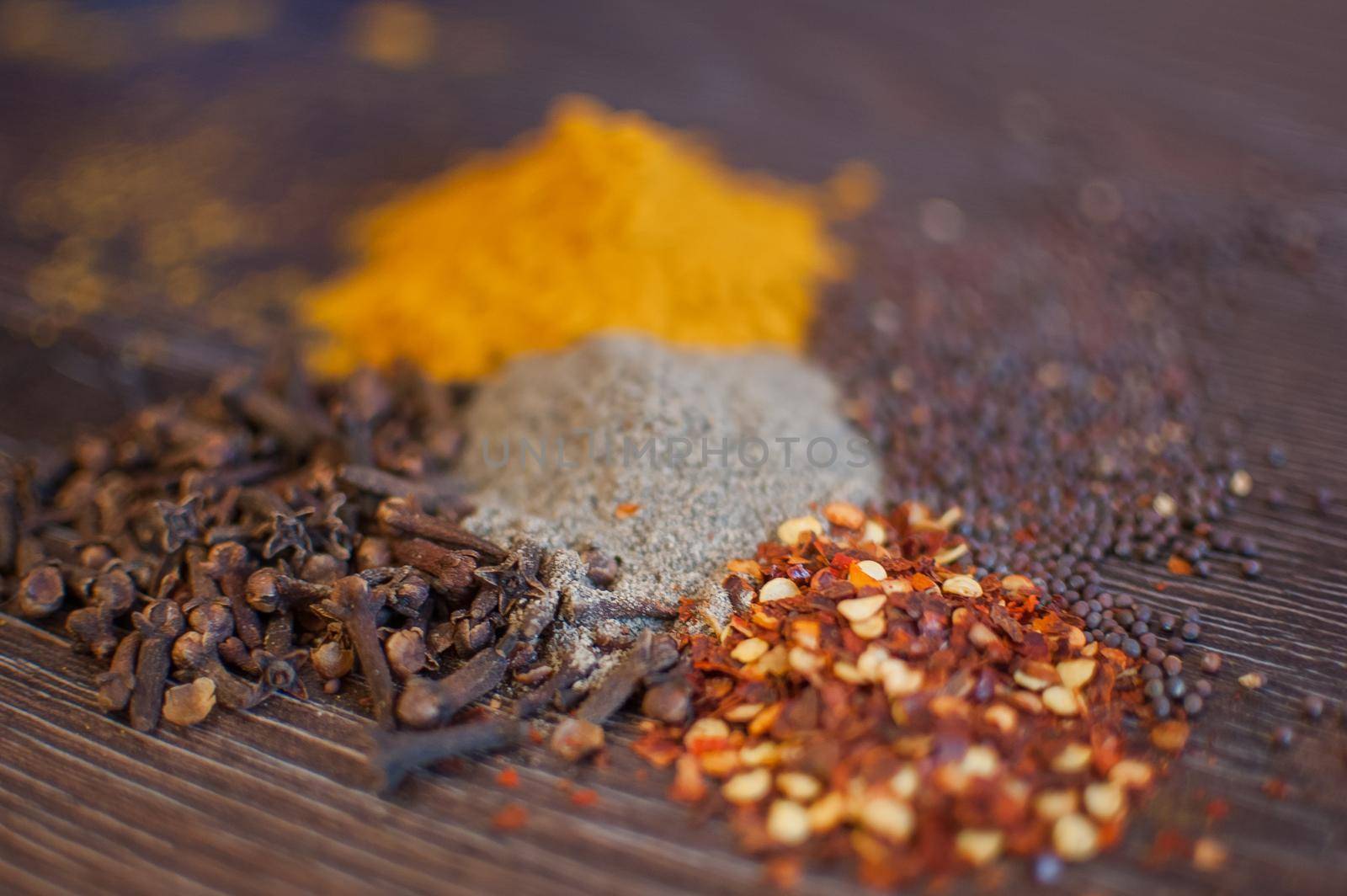 Sorted spices on dark wood background, seasonings for food. Top view of curry, paprika, pepper, cloves, bay leaf, turmeric, spices concept