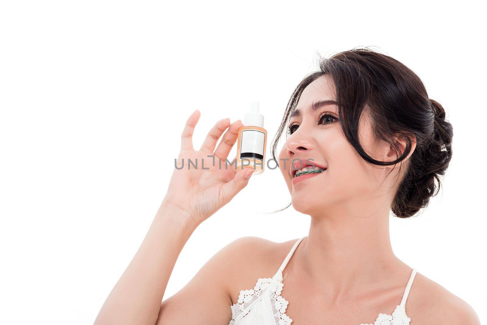 Asian young beautiful woman smiling she's holding bottle serum hair or skin care near face for present product isolated on over white background, Beauty salon concept