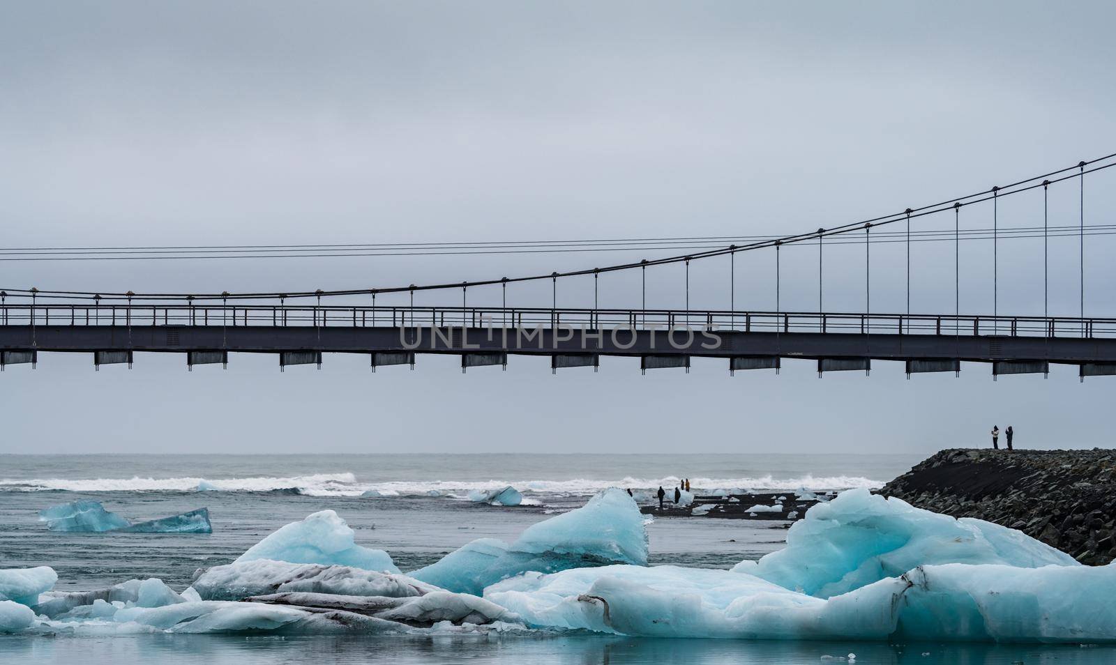 Jokulsarlon bridge, mouth and icebergs on diamond beach with unrecognizable tourists and text space