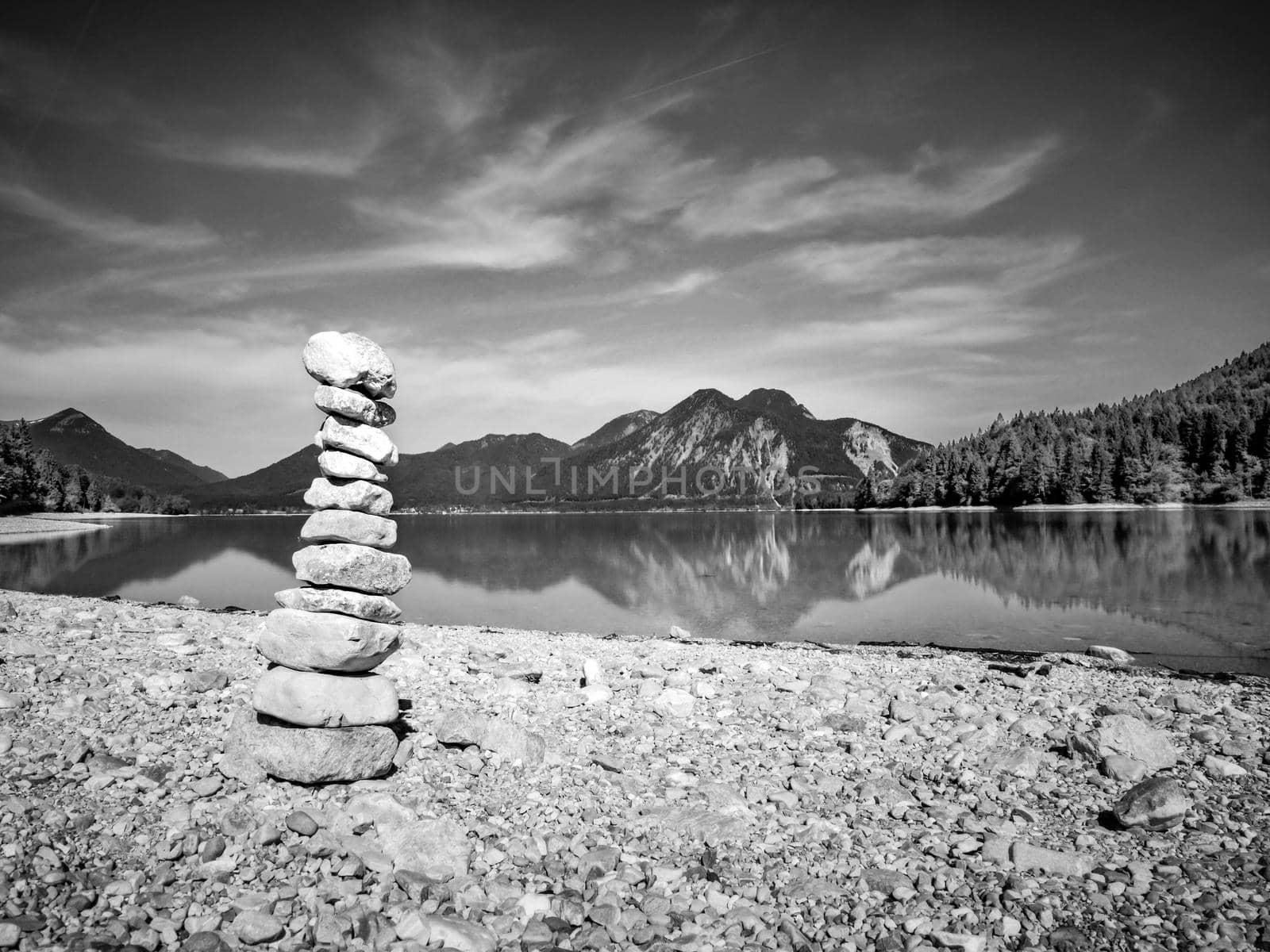 Stacked pebbles on the lake shore. Balanced stones stack at water with reflection. BW, Black and white,