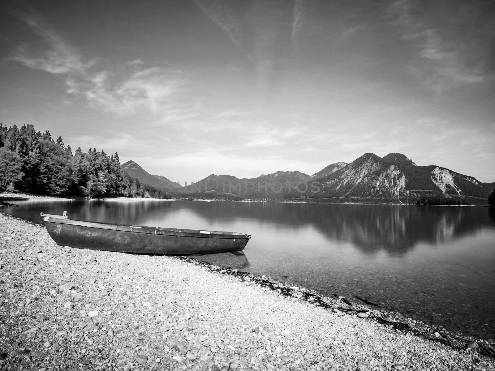 Fishing boat on shore on background of picturesque landscape of lake and green nature around in bright sunny summer day. BW, Black and white,