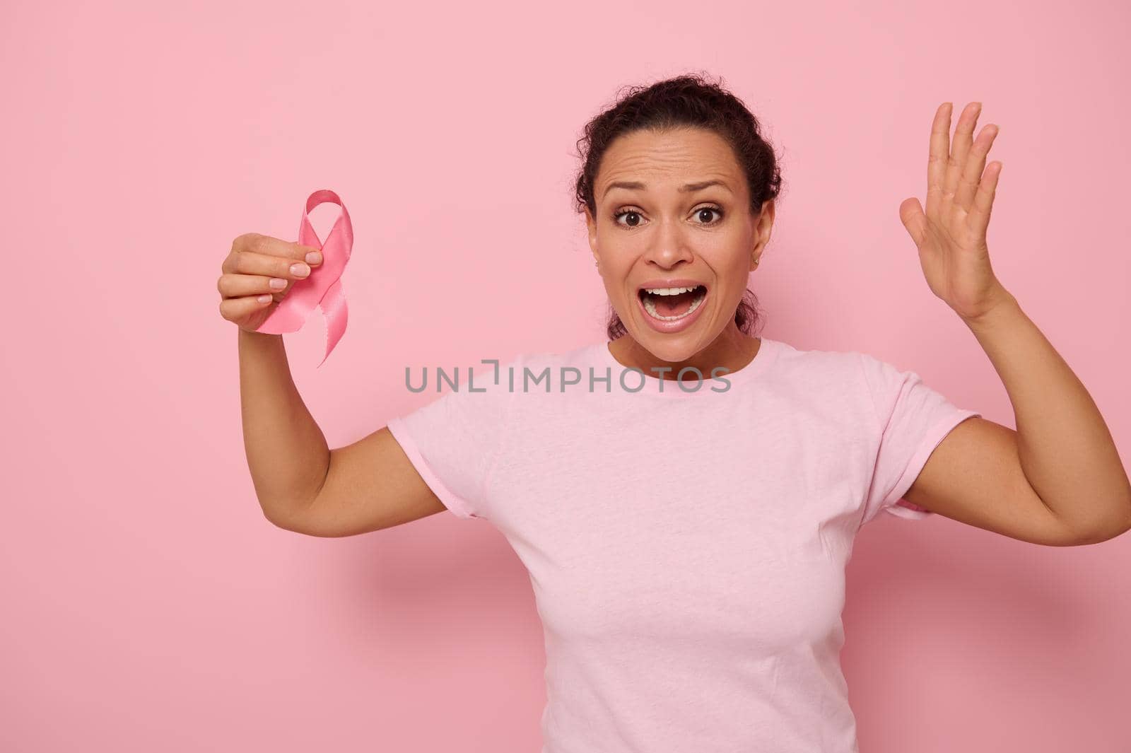 Woman in pink t-shirt holding cancer awareness pink ribbon. October Breast Cancer Awareness month, Woman in pink T- shirt with Pink Ribbon for supporting people living and illness. by artgf