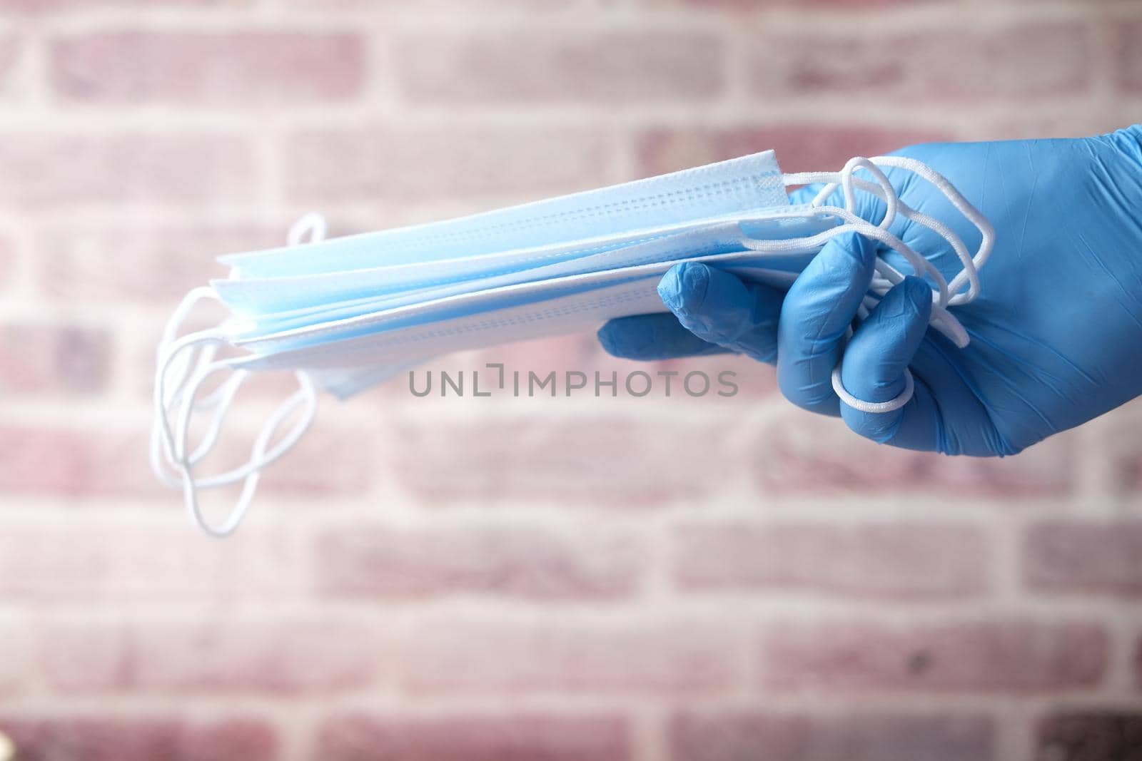 doctor hand in medical glove holding protective surgical face mask, close up .