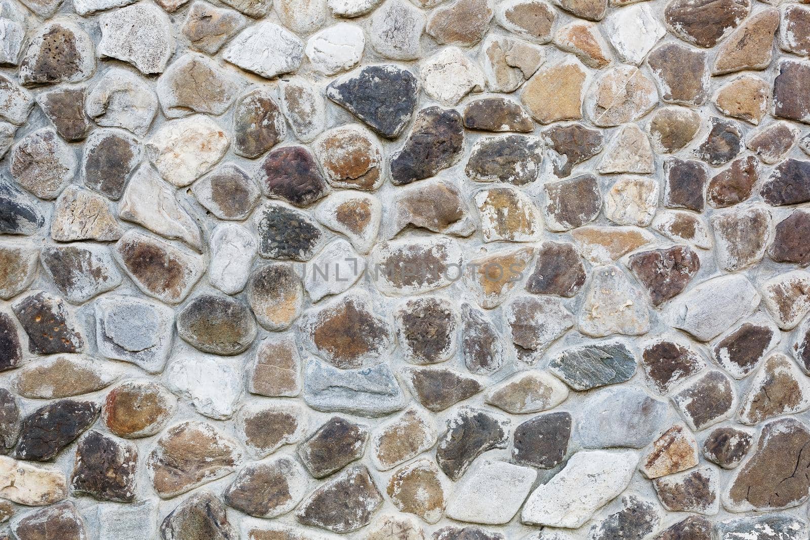 Large wall of natural stones of different size and colored gray texture on a summer day by AlexGrec