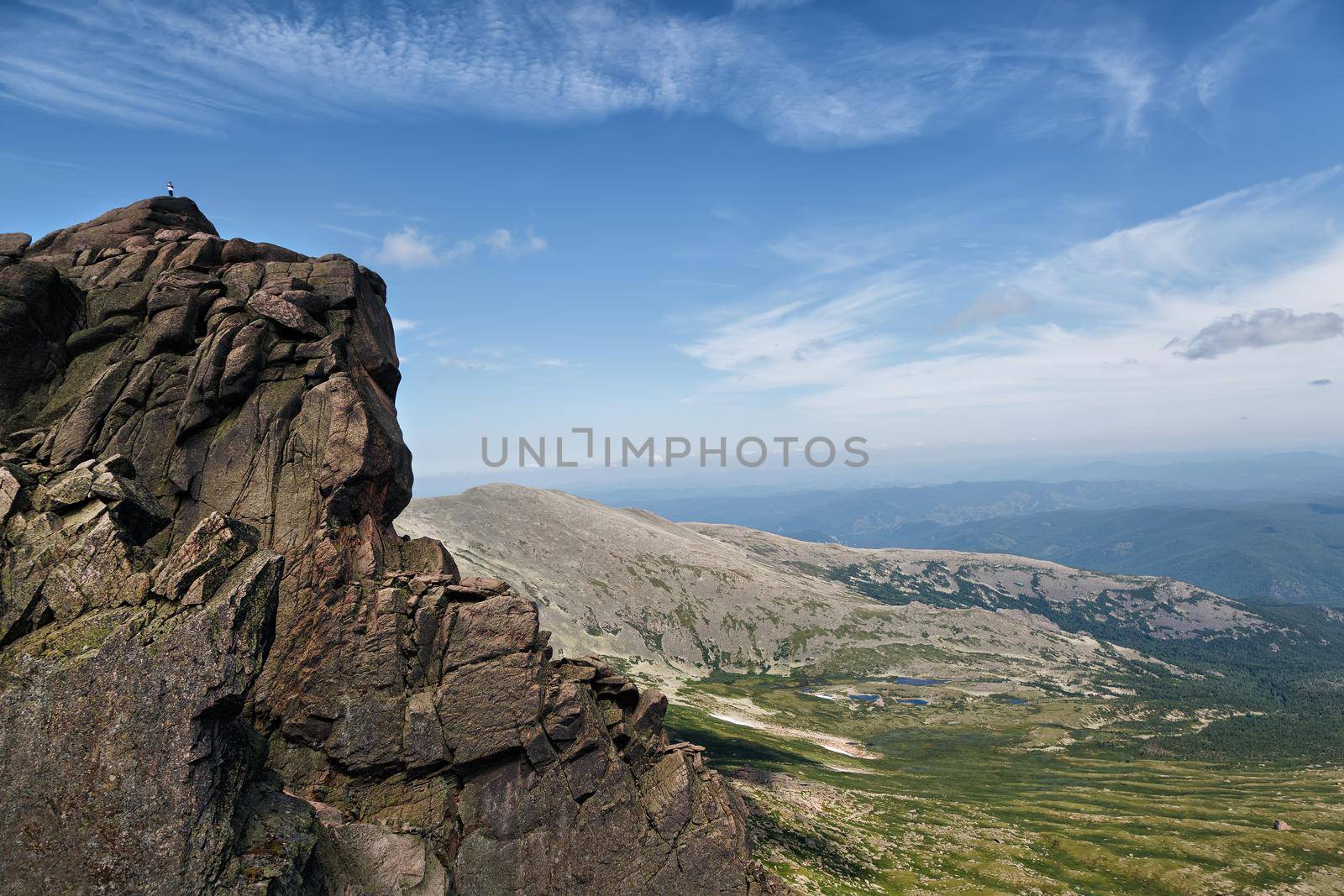 The man is high on the rock, against the background of the valley in clear weather. Conceptual design.