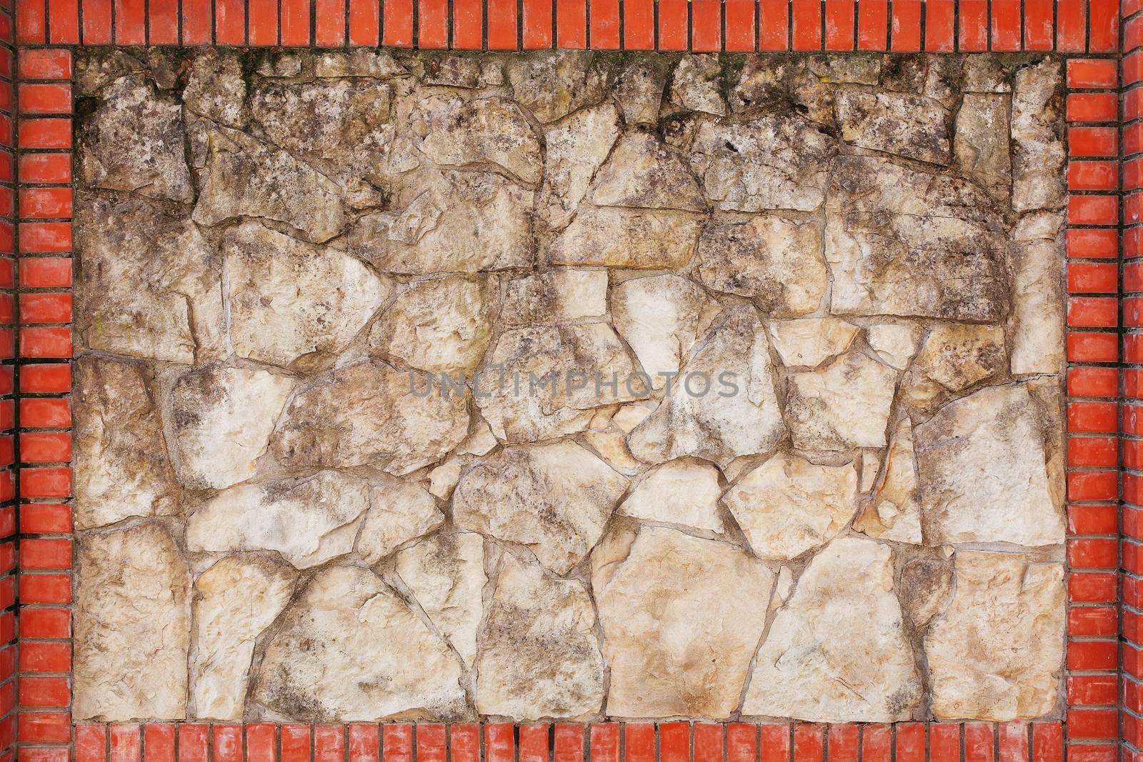Wall of natural light stone in a red brick frame. by AlexGrec