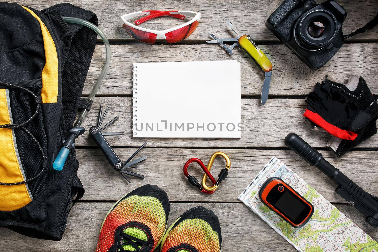 A set of accessories for cycling on a wooden background, With empty space and a notepad in the middle.