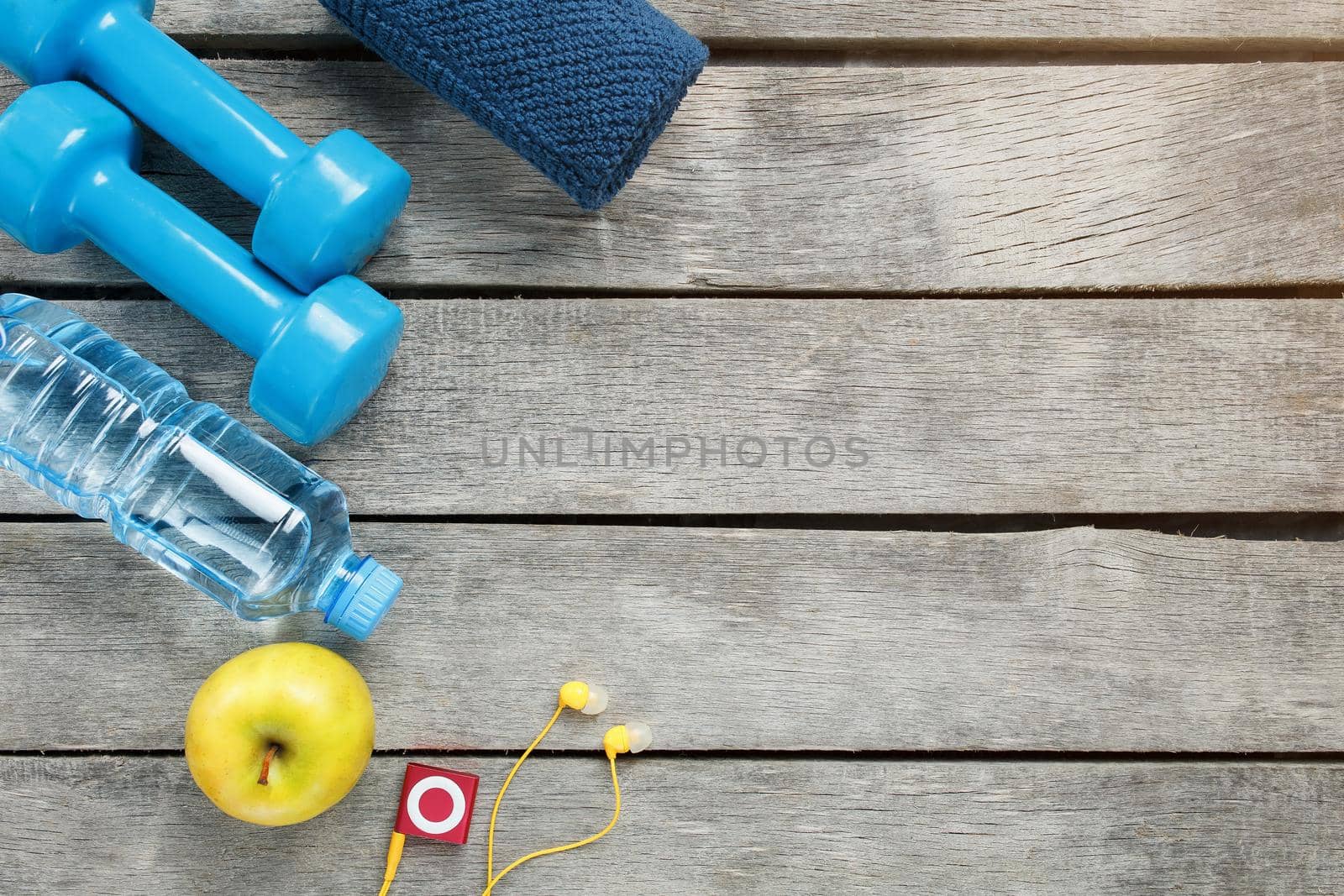 sports equipment on a gray, wooden background, dumbbells, apple water in a bottle, player, towel