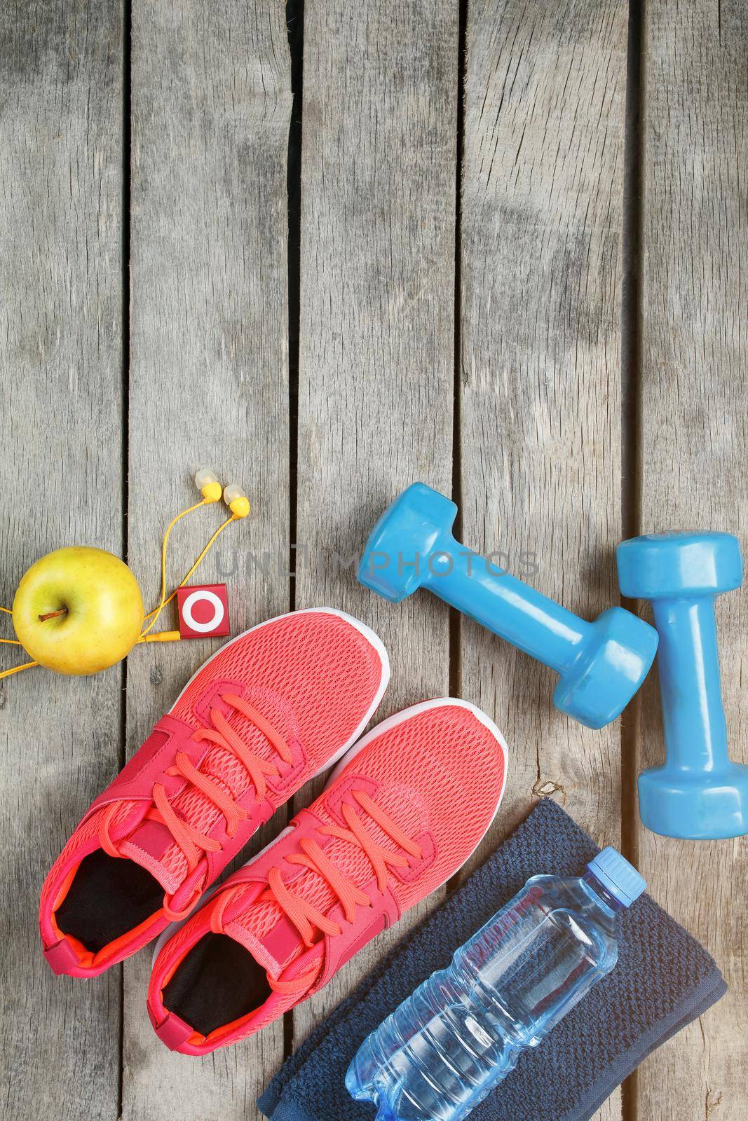 Composition with sports shoes on a wooden background, dumbbells, apple water in a bottle, player