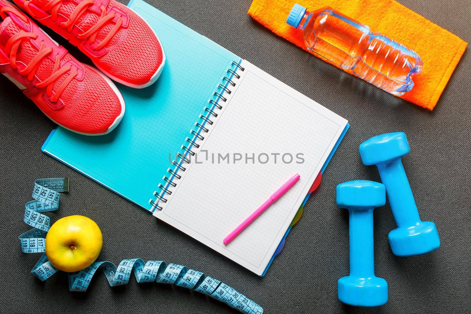 Notepad, a bottle of water, an apple, a skipping rope, dumbbells. Healthy diet, lifestyle, concept of dumbbells, exercise by AlexGrec