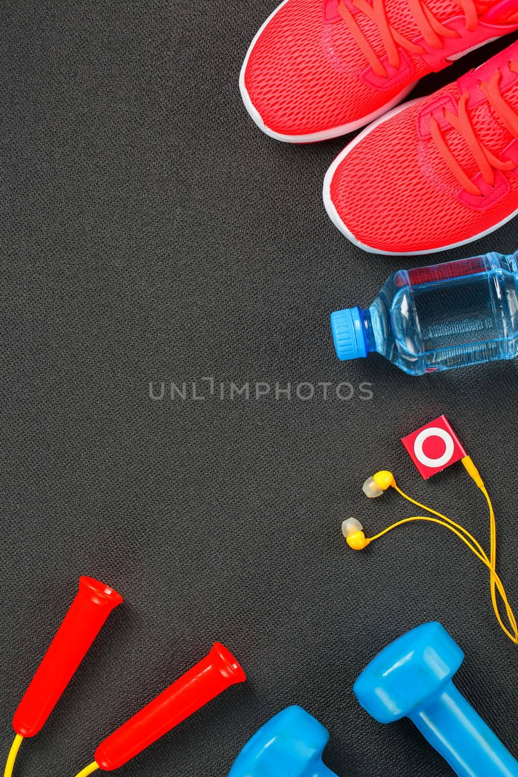 Top view of sports equipment, dumbbells, a skipping rope, a bottle of water, sneakers and a player. Isolated on a gray by AlexGrec
