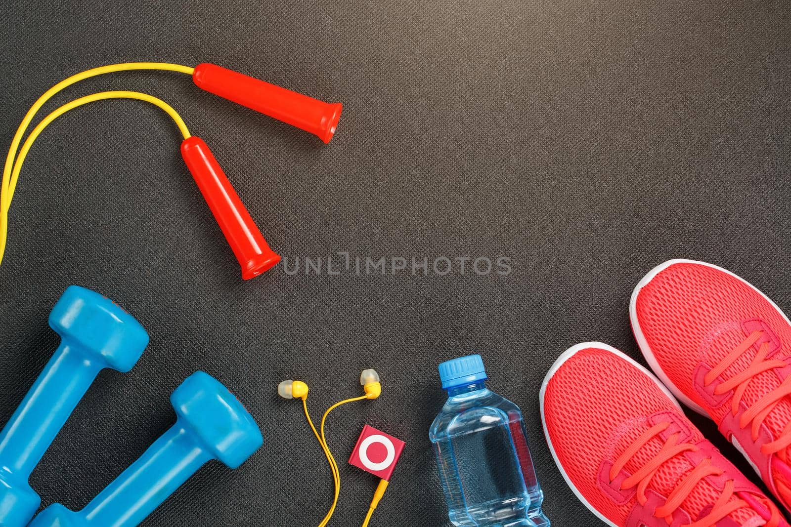 Top view of sports equipment, dumbbells, a skipping rope, a bottle of water, sneakers and a player. Isolated on a gray by AlexGrec