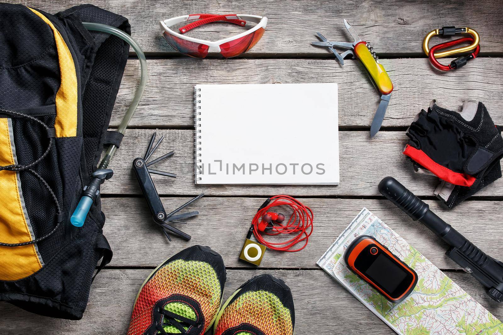 A set of accessories for cycling on a wooden background, With empty space and a notepad in the middle.