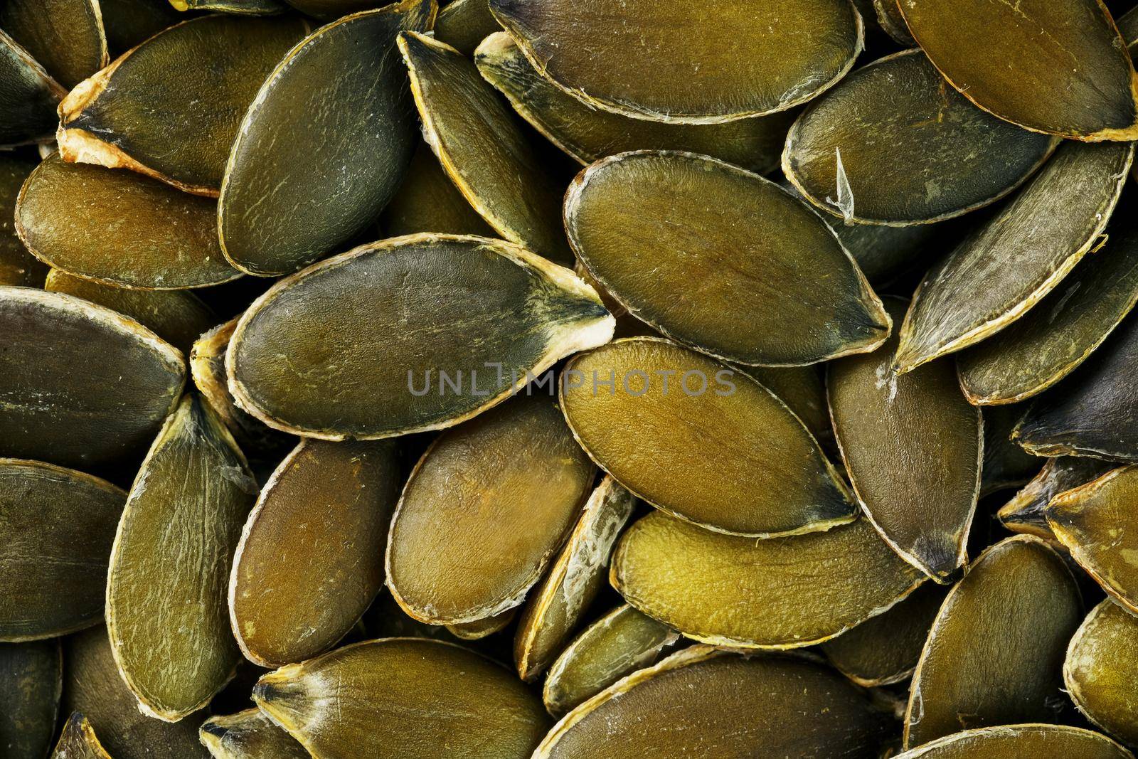 Macro background texture of green pumpkin seeds. Organic vegan food.