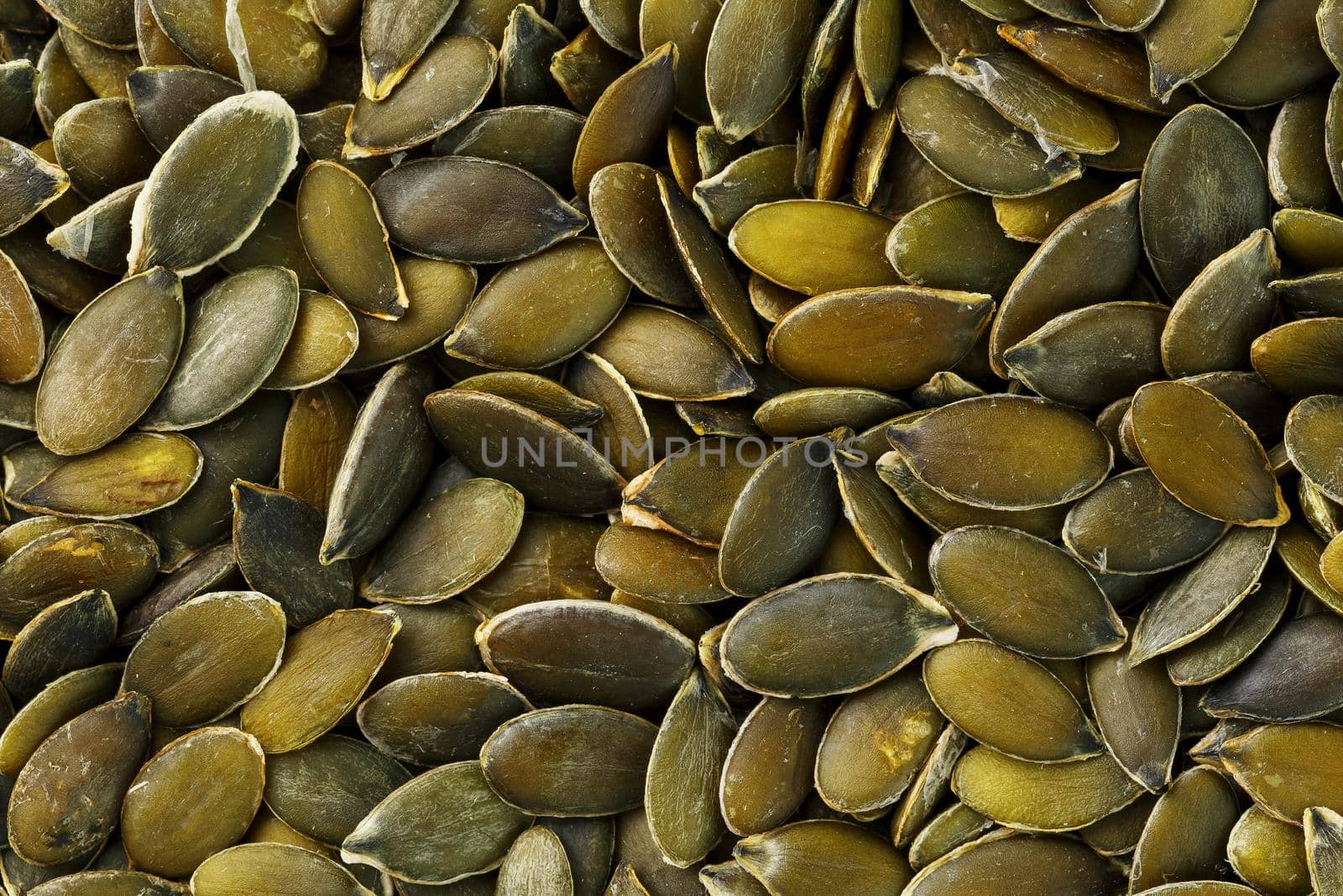 Macro background texture of green pumpkin seeds. Organic vegan food.