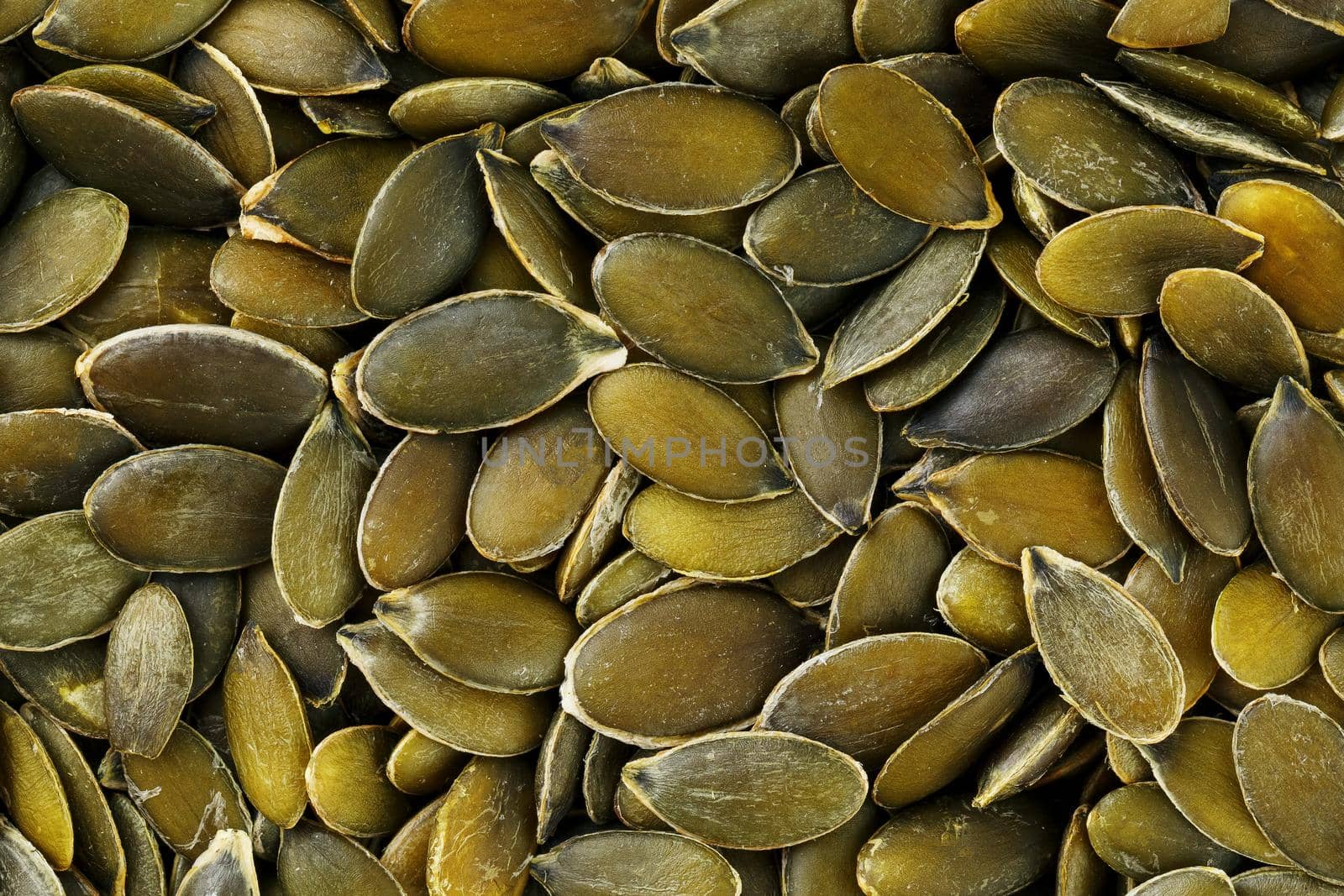 Macro background texture of green pumpkin seeds. Organic vegan food.