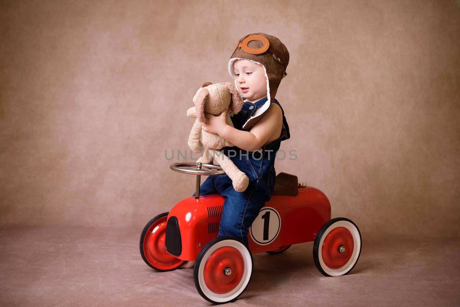 Child riding in red car. Kid holding Christmas bag. Xmas holiday concept by jcdiazhidalgo