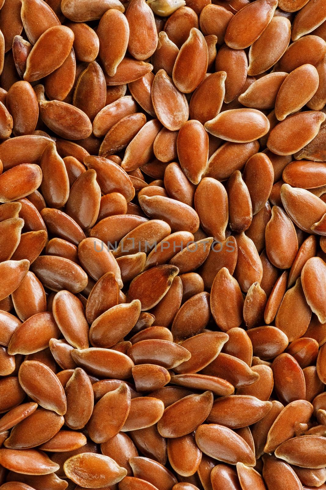 Background texture of seeds of dark brown flax. Grain on butter. Useful cereals.