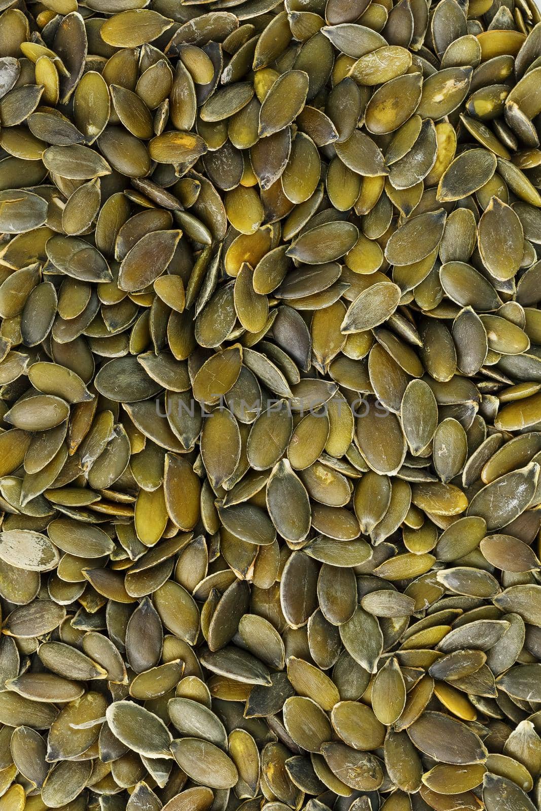 Macro background texture of green pumpkin seeds. Organic vegan food.