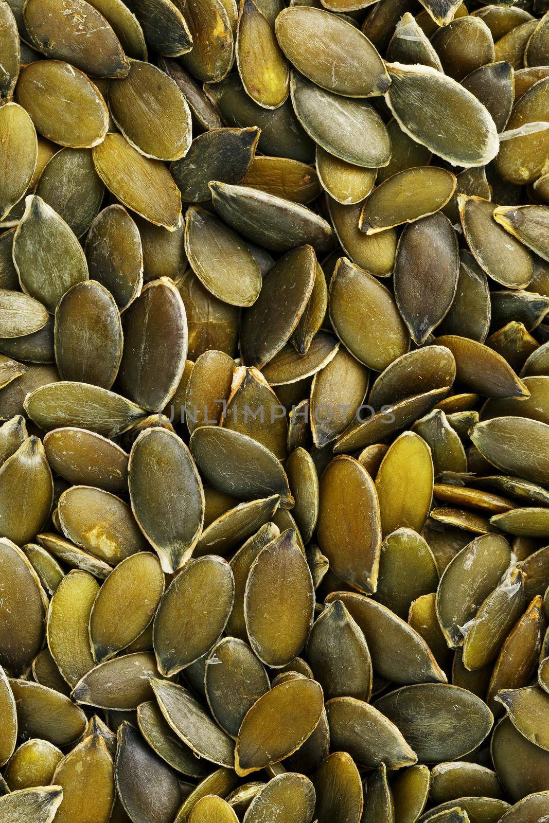 Macro background texture of green pumpkin seeds. Organic vegan food.