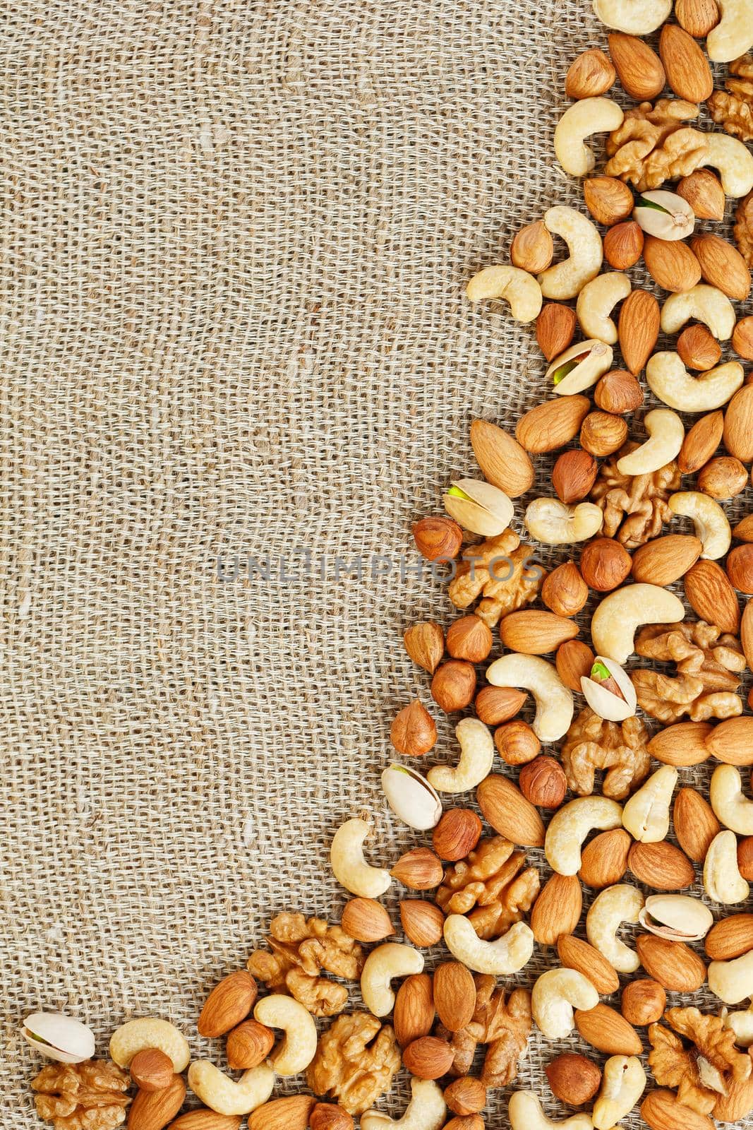 Mix of nuts lying on a background of brown cloth burlap. by AlexGrec