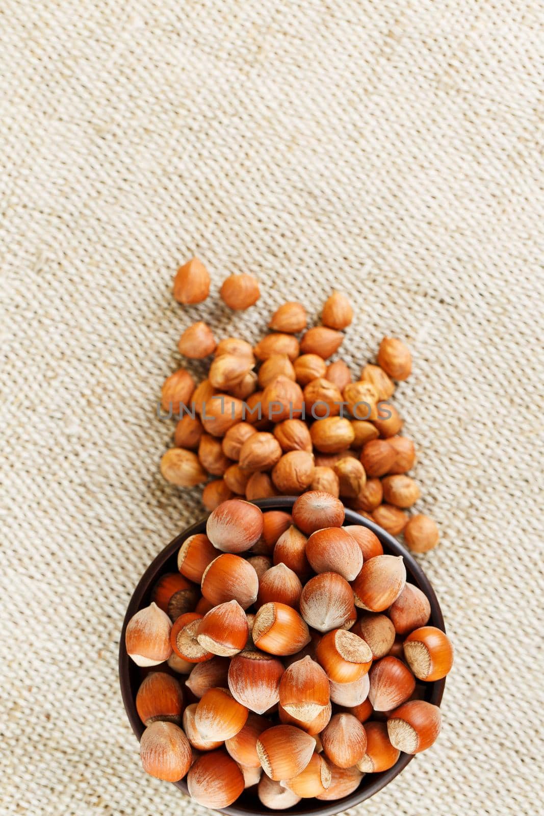 Peeled hazelnuts in a wooden, dark brown cup on a burlap cloth. Super Food, Raw. View from above.