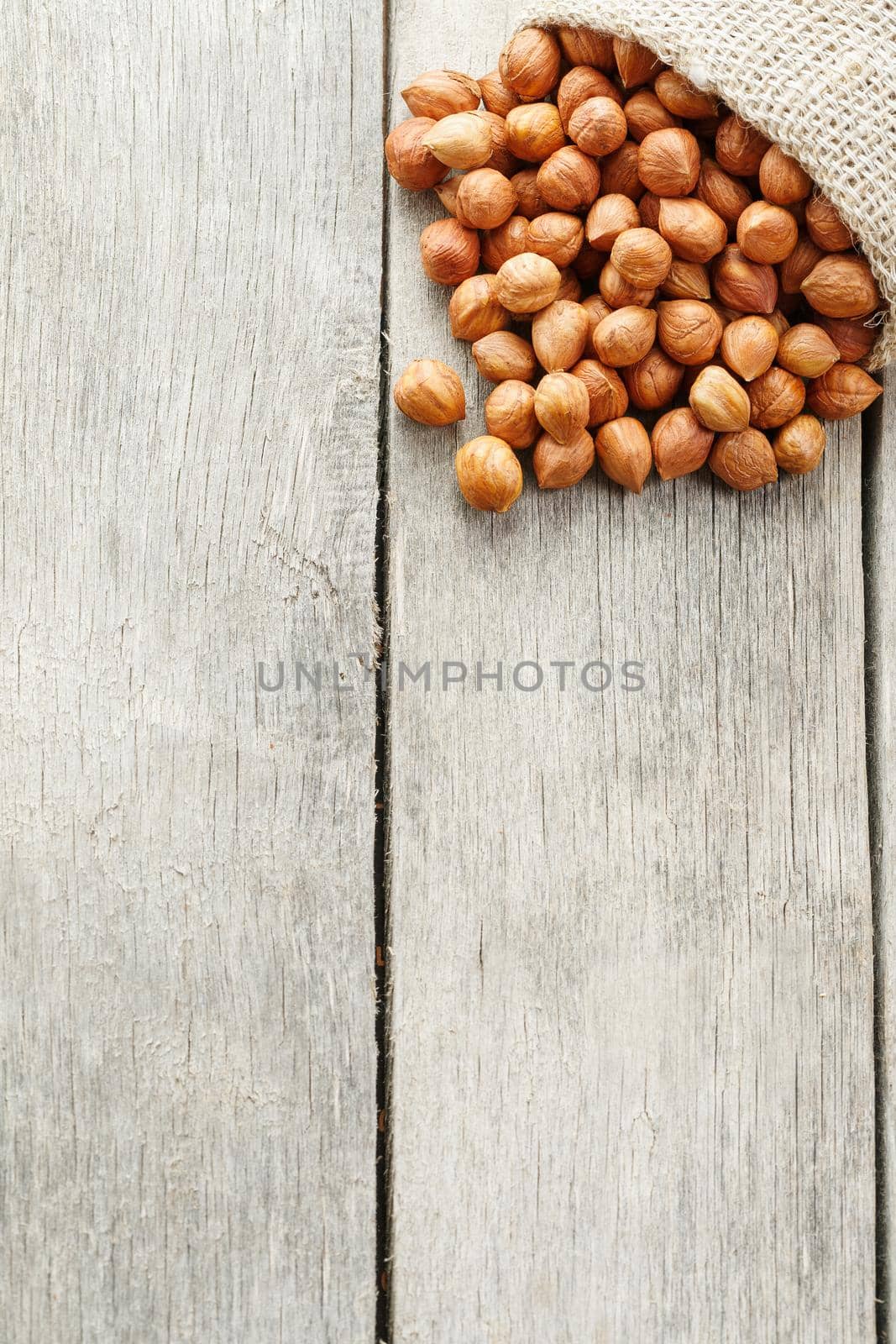 Chiselled hazelnuts in a bag of burlap on a gray wooden table. Organic Fresh Harvested. Without shell healthy vegetarian super food.