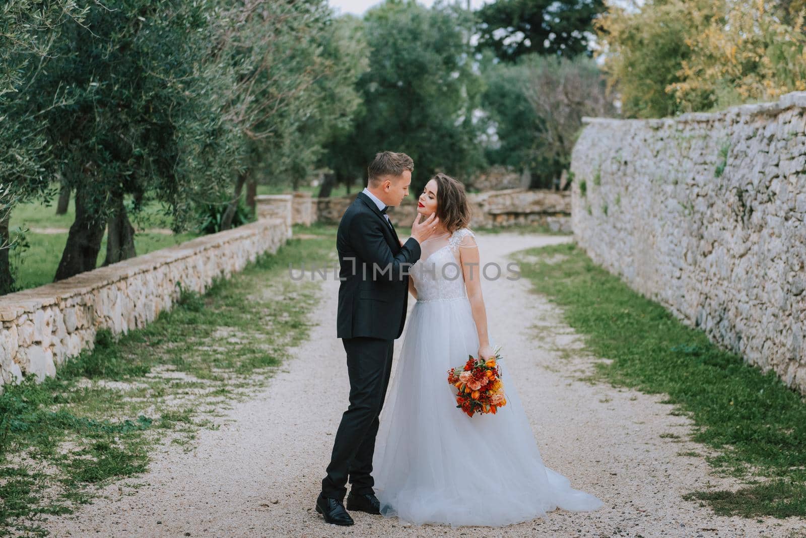 Happy stylish smiling couple walking in Tuscany, Italy on their wedding day. The bride and groom walk down the street by the hands. A stylish young couple walks. Husband and wife communicate nicely. Lovers run through the streets of the city.