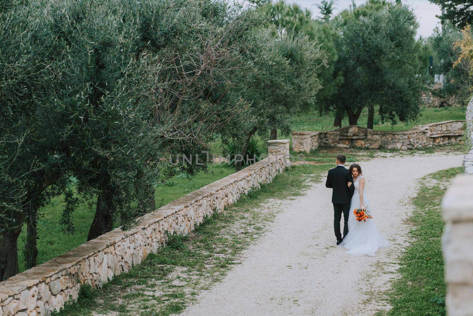 Happy stylish smiling couple walking in Tuscany, Italy on their wedding day. The bride and groom walk down the street by the hands. A stylish young couple walks. Husband and wife communicate nicely. Lovers run through the streets of the city.