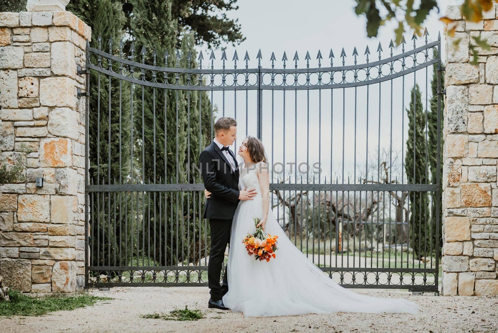 Happy stylish smiling couple walking in Tuscany, Italy on their wedding day. The bride and groom walk down the street by the hands. A stylish young couple walks. Husband and wife communicate nicely. Lovers run through the streets of the city by Andrii_Ko