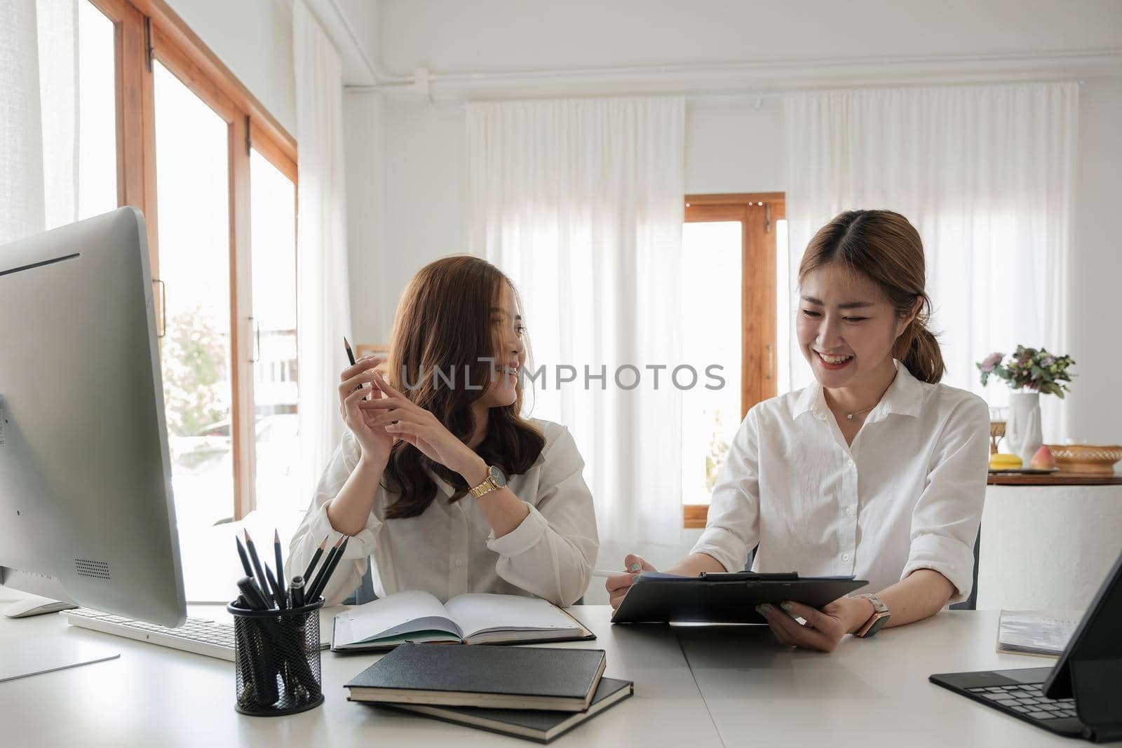 Two asian business partnership coworkers discussing a financial planning graph and company during a budget meeting in office room. working together meeting concept