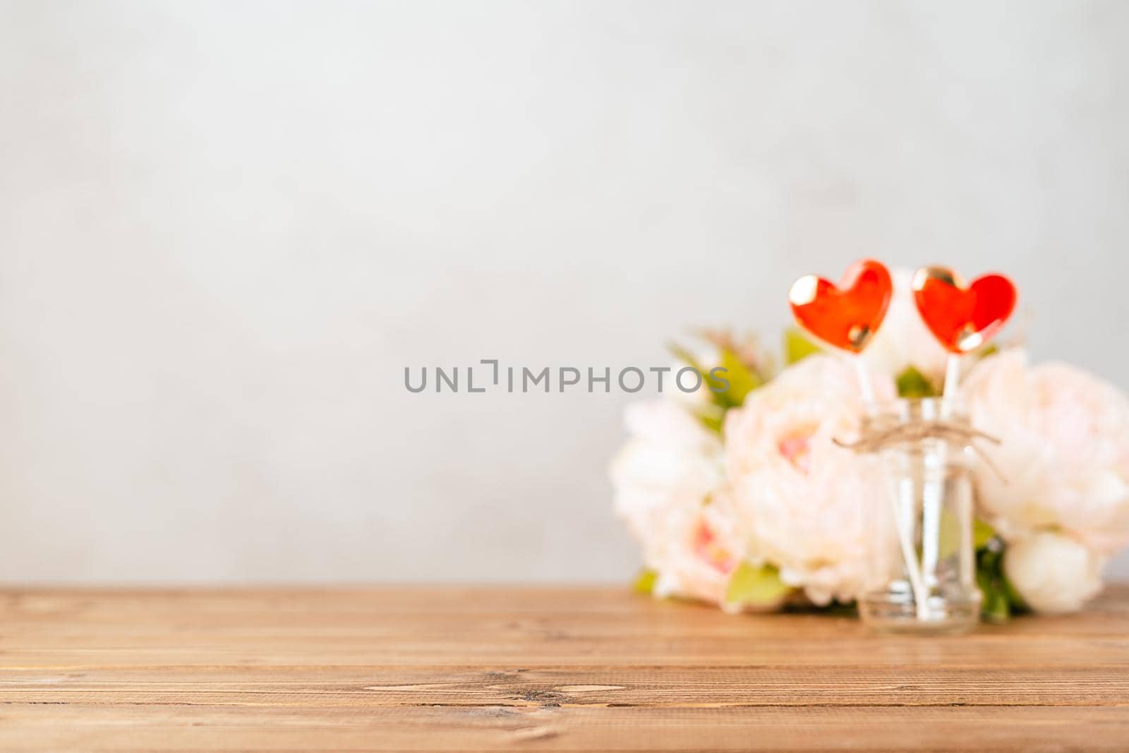 Still life Valentines day festive empty background with 2 red lollipop and pink flowers on wooden table background. Mockup with copy space for design. Defocused banner.
