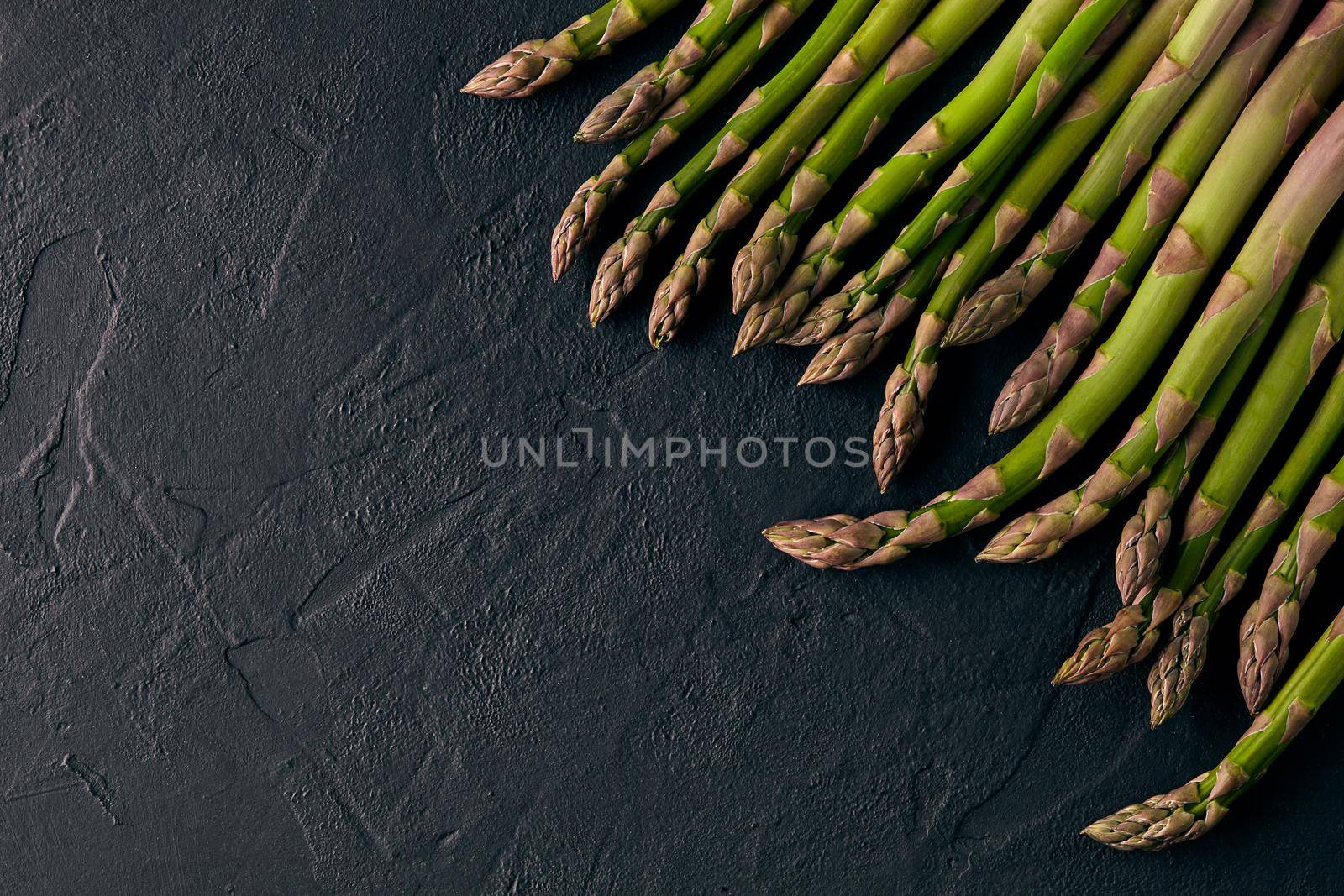 Asparagus stems against black slate background. Concept of healthy nutrition, food and seasonal vegetables harvest. Close up, copy space. Flat lay, top view