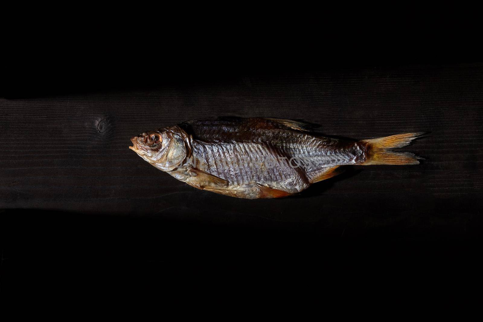 One dried or jerky salted taranka, yummy clipfish on wooden background. Salty beer snack. Traditional way of preserving fish. Close up, top view