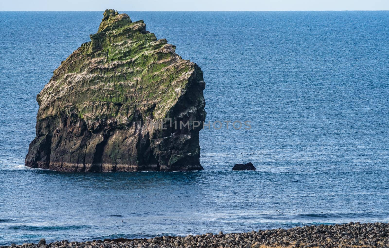 Huge boulder near the coastline with huge ocean