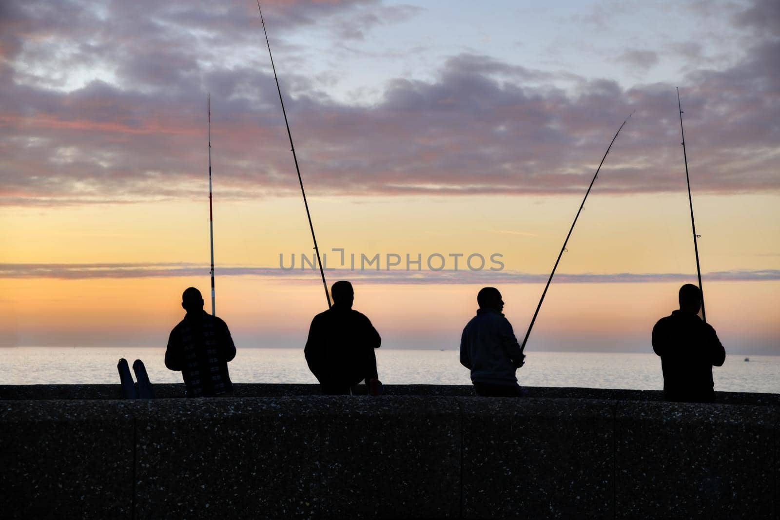 Fishermen fishing at a vanilla sunset on the Atlantic Ocean by Godi