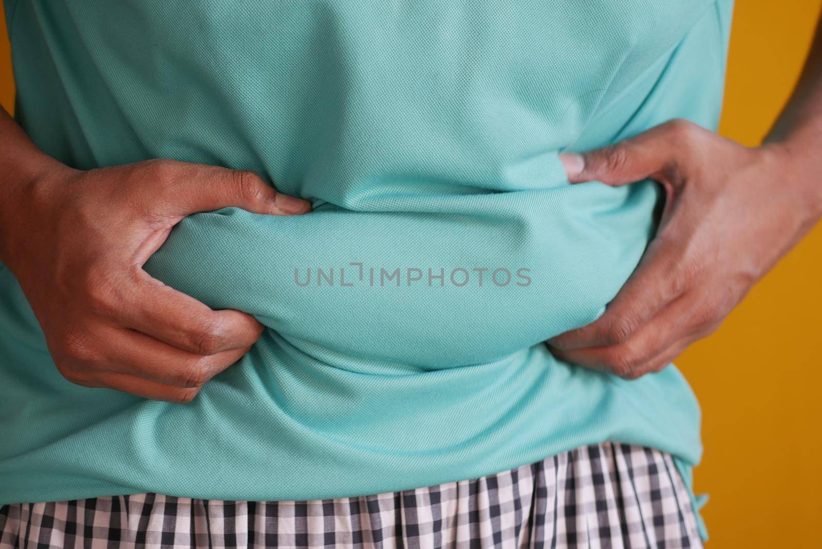 man's hand holding excessive belly fat, overweight concept.