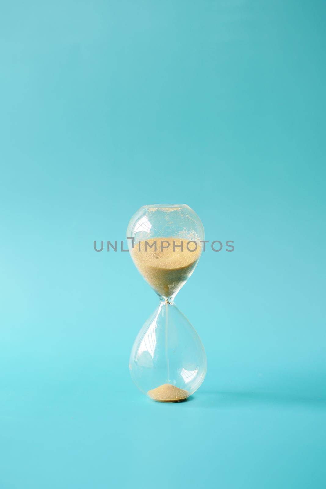 hourglass on table, sand flowing through the bulb of sandglass by towfiq007