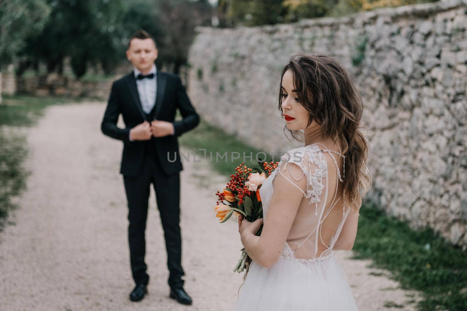 Happy stylish smiling couple walking in Tuscany, Italy on their wedding day. The bride and groom walk down the street by the hands. A stylish young couple walks. Husband and wife communicate nicely. Lovers run through the streets of the city by Andrii_Ko