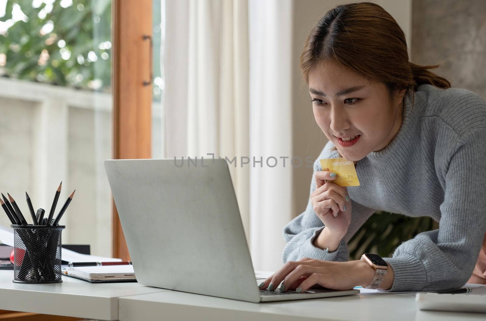 Close up image of a happy woman holding credit card while using laptop computer. online shopping with cash back, discount sales, low prices, saving money. Money back concept