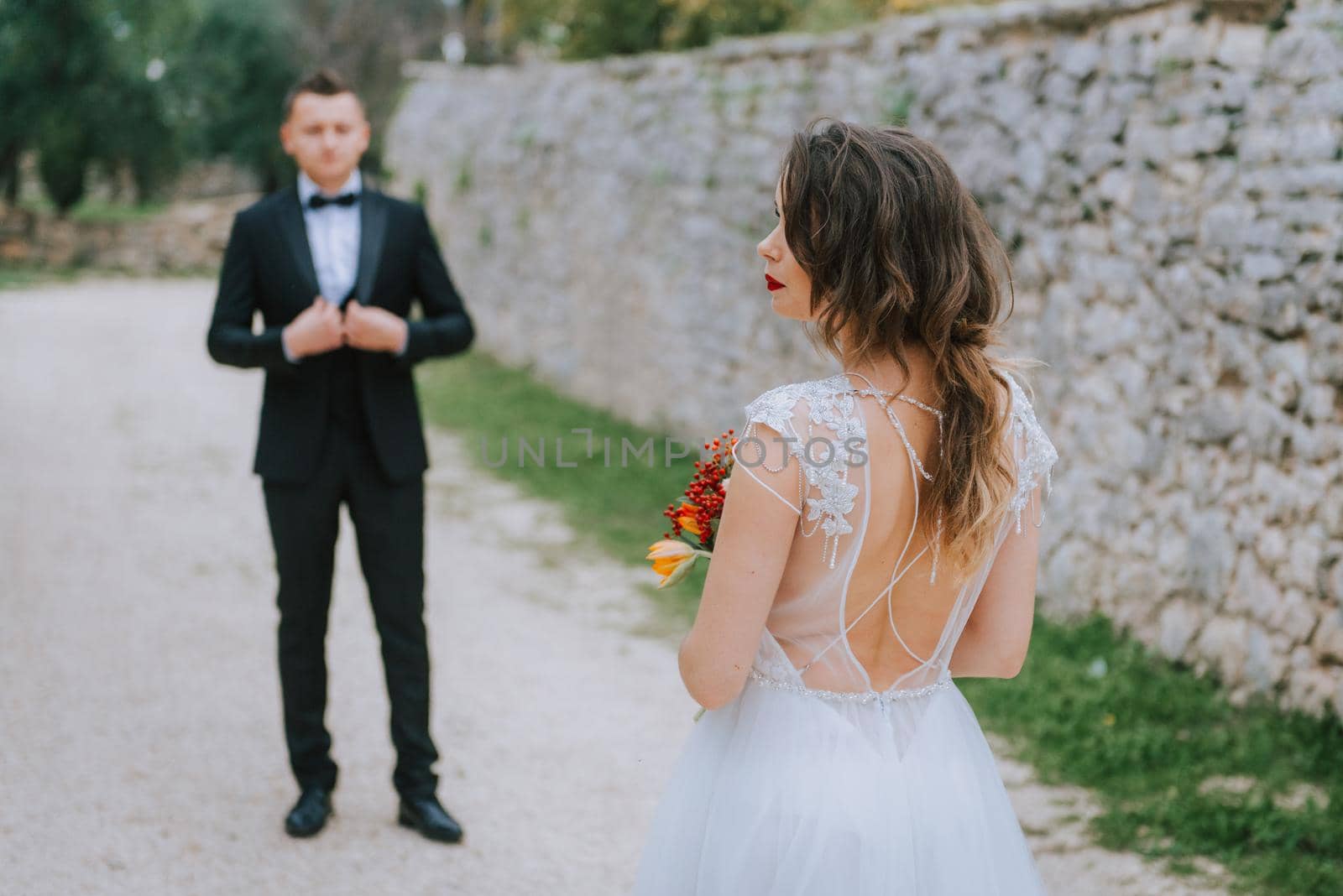 Happy stylish smiling couple walking in Tuscany, Italy on their wedding day. The bride and groom walk down the street by the hands. A stylish young couple walks. Husband and wife communicate nicely. Lovers run through the streets of the city.