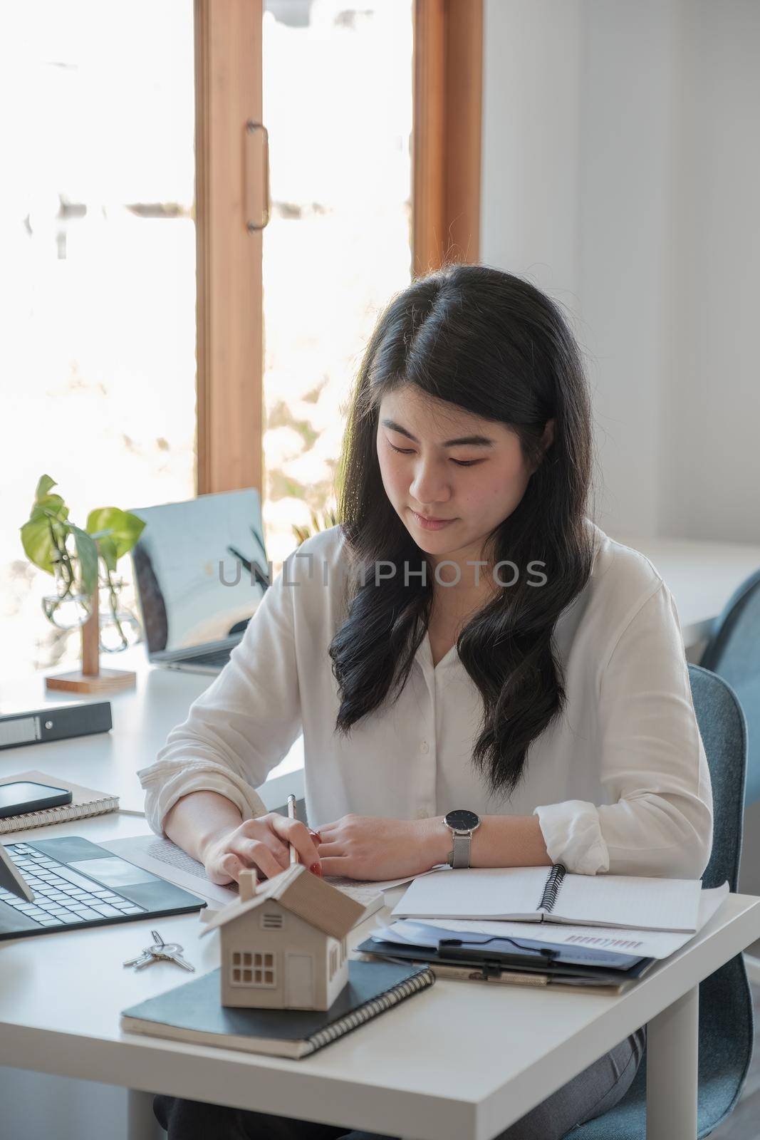 Business asian woman using calculating interest, taxes and profits to invest in real estate and home buying