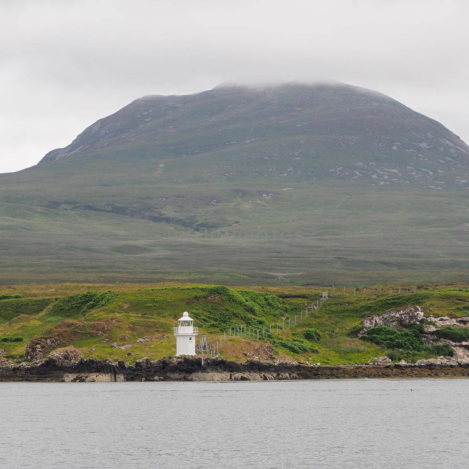 Carragh an t-Sruith lighthouse in the Sound of Islay near Feolin, Jura sits under the mountain shrouded in cloud, Hebrides, Scotland, UK