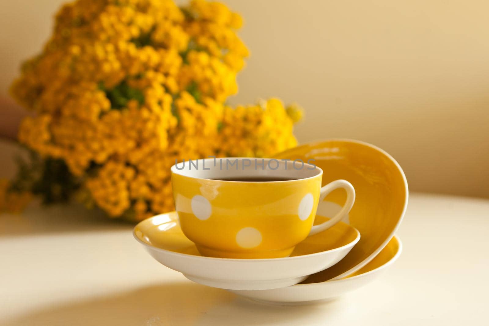 yellow cup levitation with black tea. retro tea-set with flowers. vintage ceramic mug and plates on the table