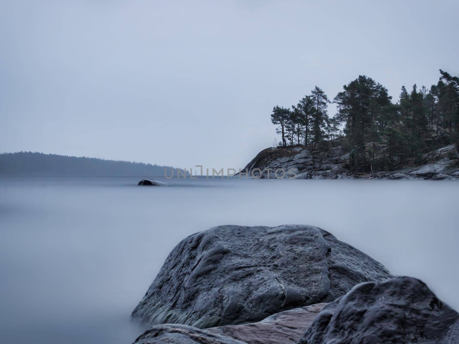 Lake Ladoga on a cloudy day. Stones and water are like fog. Long exposure.