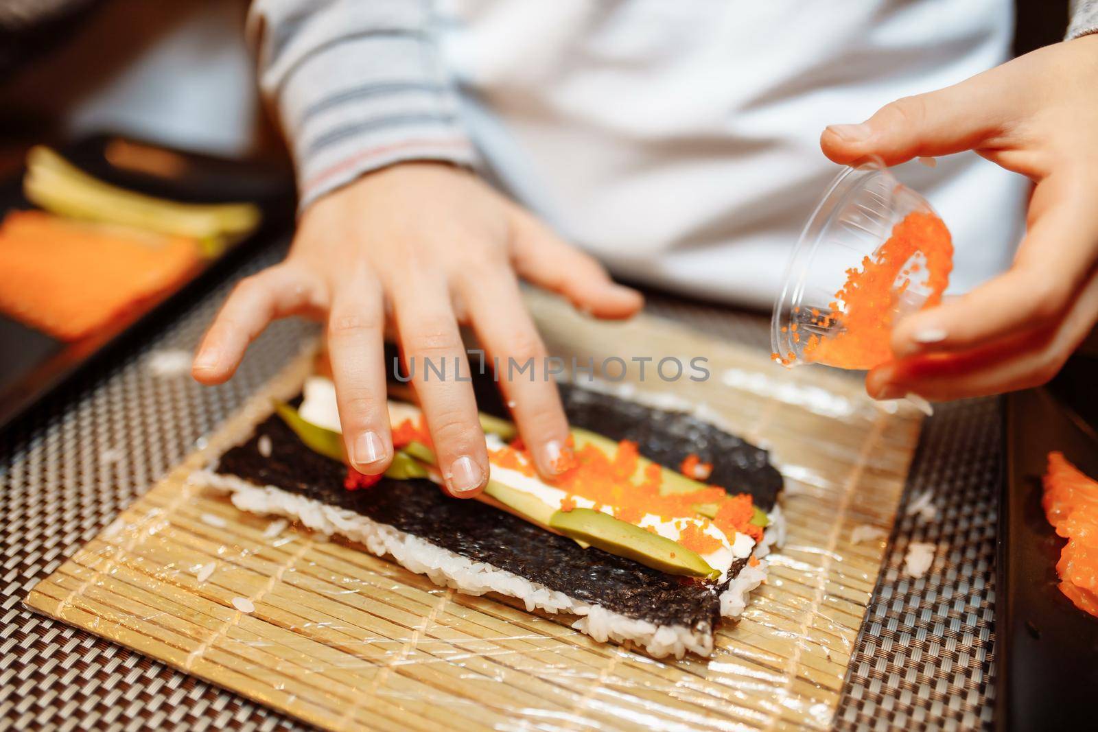 Children making sushi at the master class. Children, education and entertainment concept by UcheaD