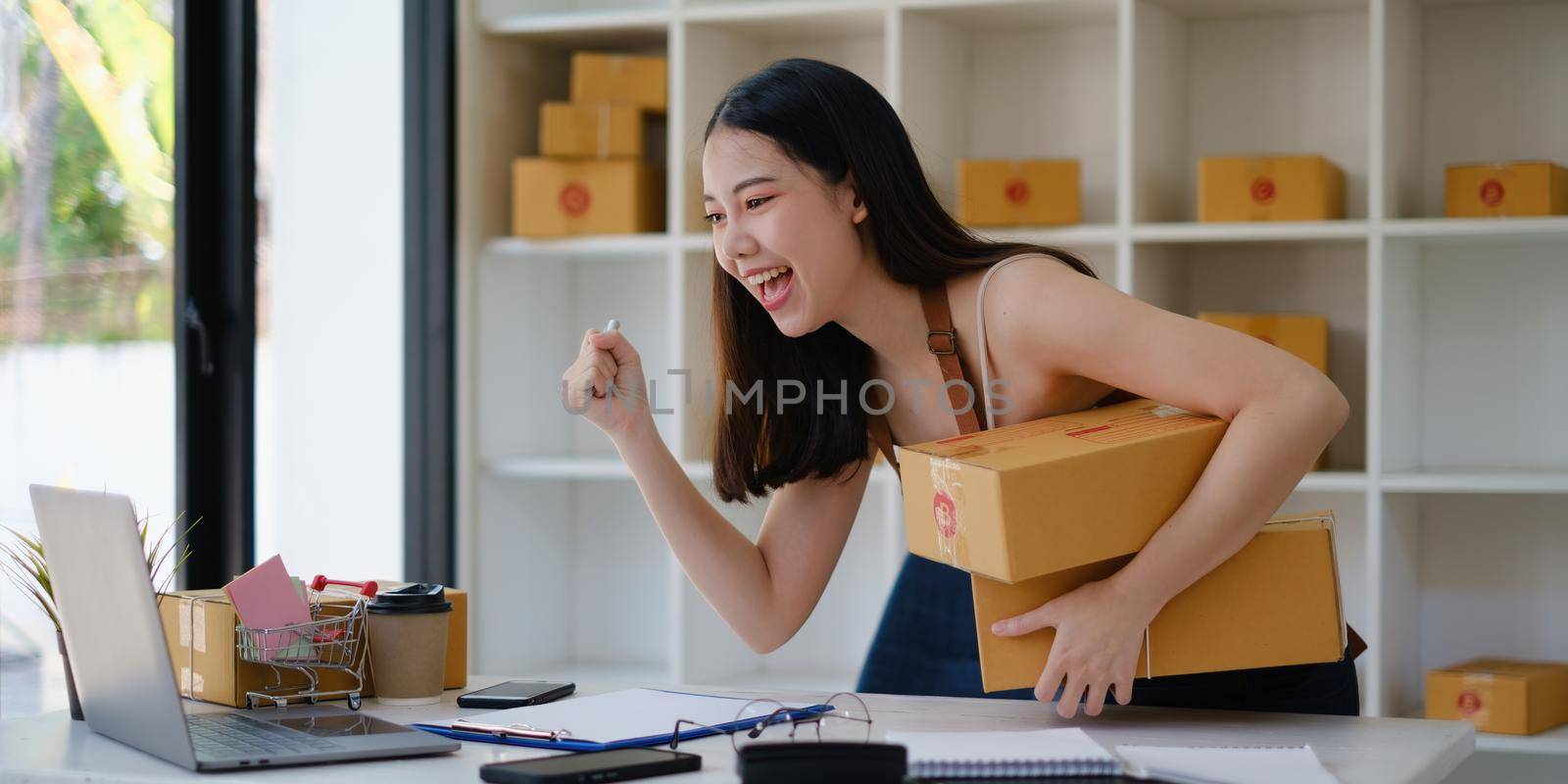 Small business owner with parcel box and working at her home to packing order before send to customer. Freelance working and SME entrepreneur concept.. by itchaznong