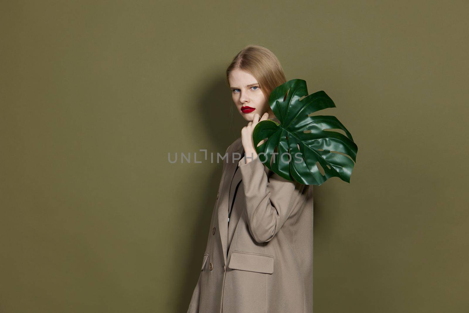 fashionable woman green palm leaf coat bright makeup studio model unaltered. High quality photo