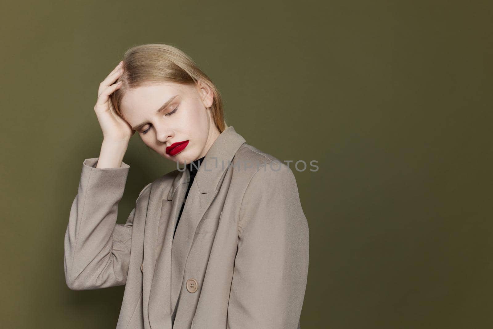 blonde woman with red lips holds hand near face isolated background by SHOTPRIME